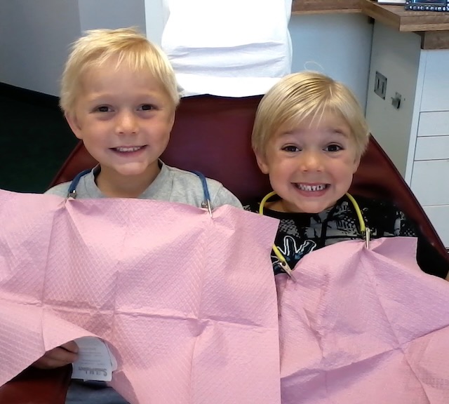 two kids in dental chair with bibs